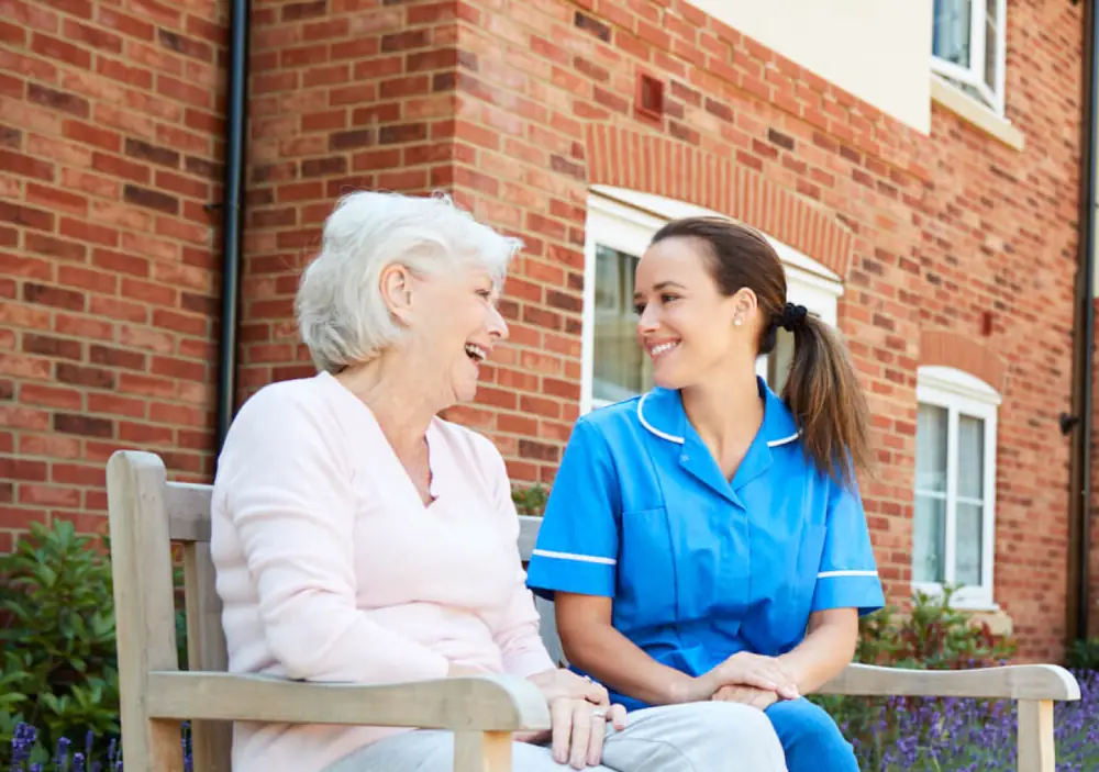 Two people sitting on a bench, talking and smiling